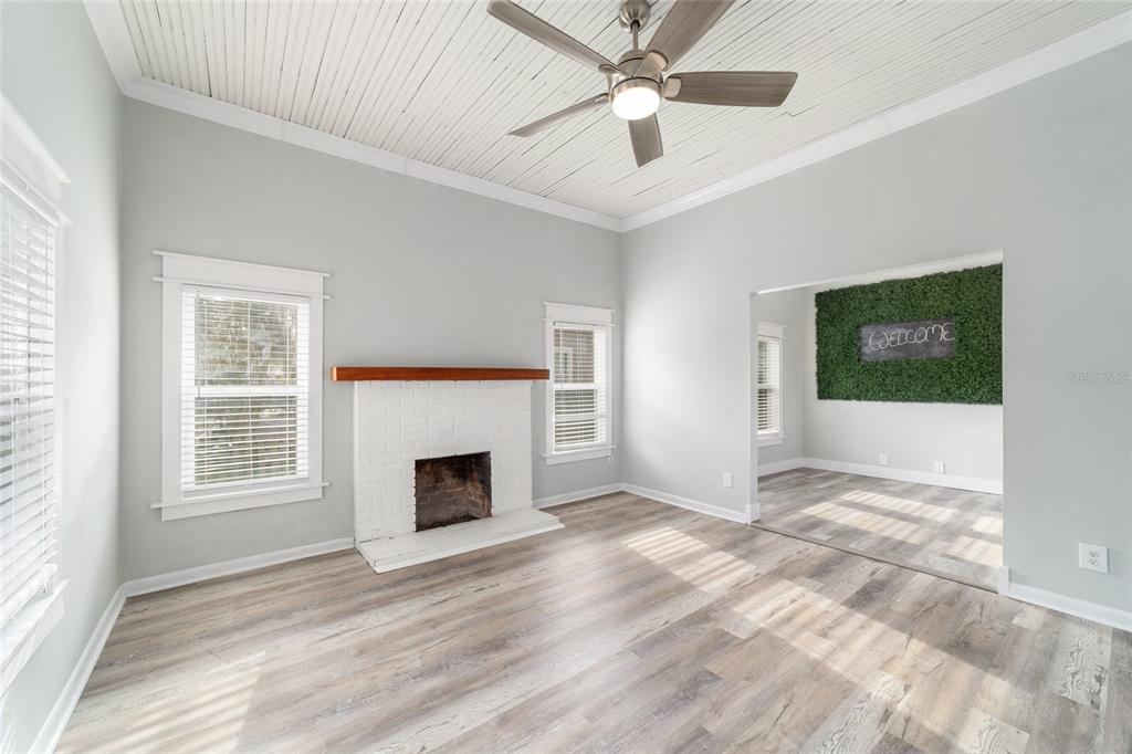 A living room with a white brick fireplace, wood-look flooring, and a ceiling fan — 20837 WALNUT STREET, DUNNELLON, FL