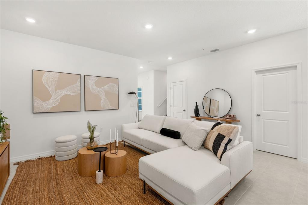 A modern living room features a white sectional sofa, a jute rug, and abstract wall art — 731 BLISSFUL GARDENS WAY, APOPKA, FL
