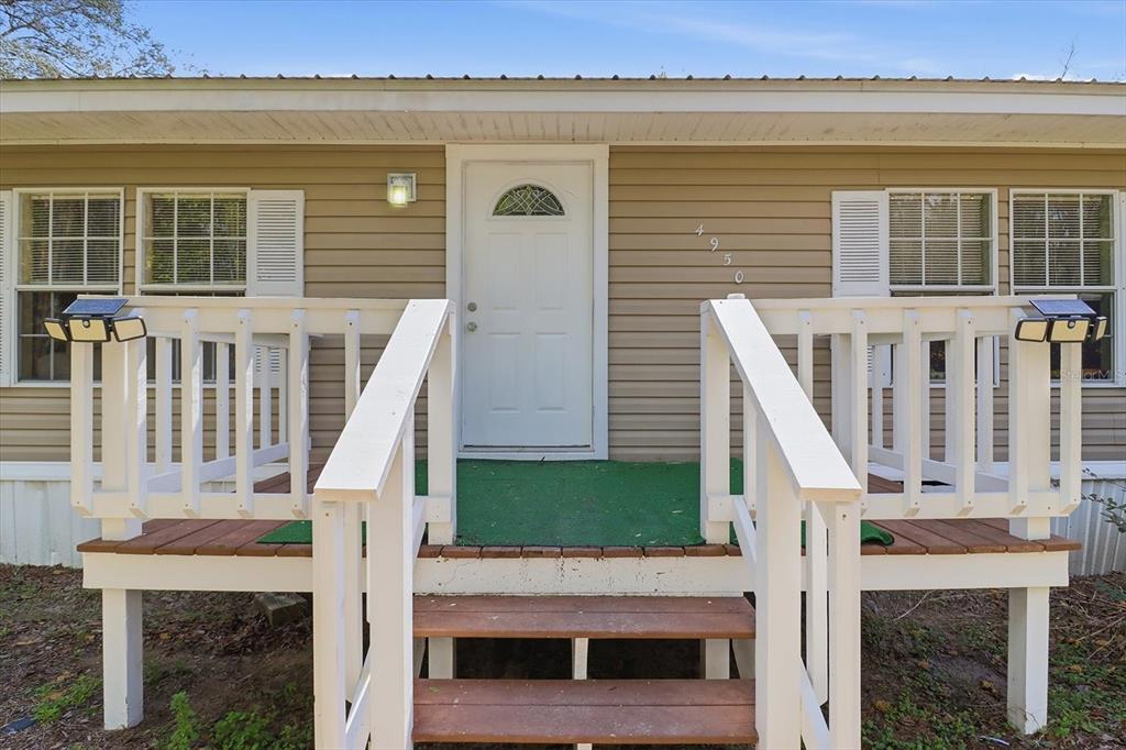 A tan house exterior features a white front door, wooden steps, and a white railing — 4950 W MOCKINGBIRD STREET, HOMOSASSA, FL