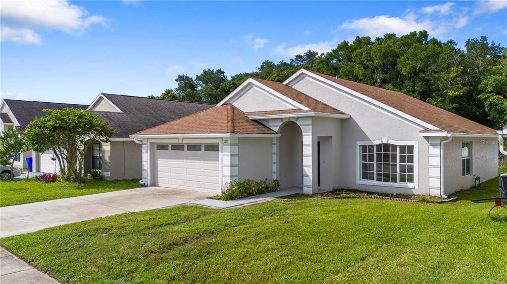 A single-story house with a tan stucco exterior, brown roof, and a two-car garage — 2016 LOCUST BERRY DRIVE, KISSIMMEE, FL