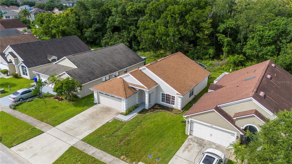 An aerial view shows three suburban houses with brown roofs and green lawns — 2016 LOCUST BERRY DRIVE, KISSIMMEE, FL