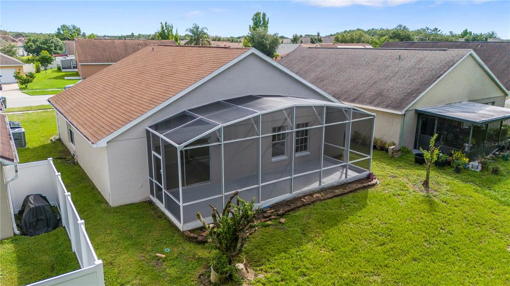 An exterior view of a house with a screened-in back patio and a fenced yard — 2016 LOCUST BERRY DRIVE, KISSIMMEE, FL