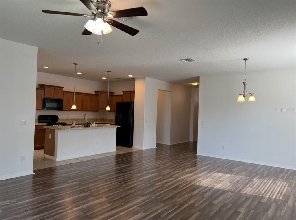 An open-concept kitchen with wood cabinets and a breakfast bar overlooks a living area — 2735 CARRICKTON CIRCLE, ORLANDO, FL