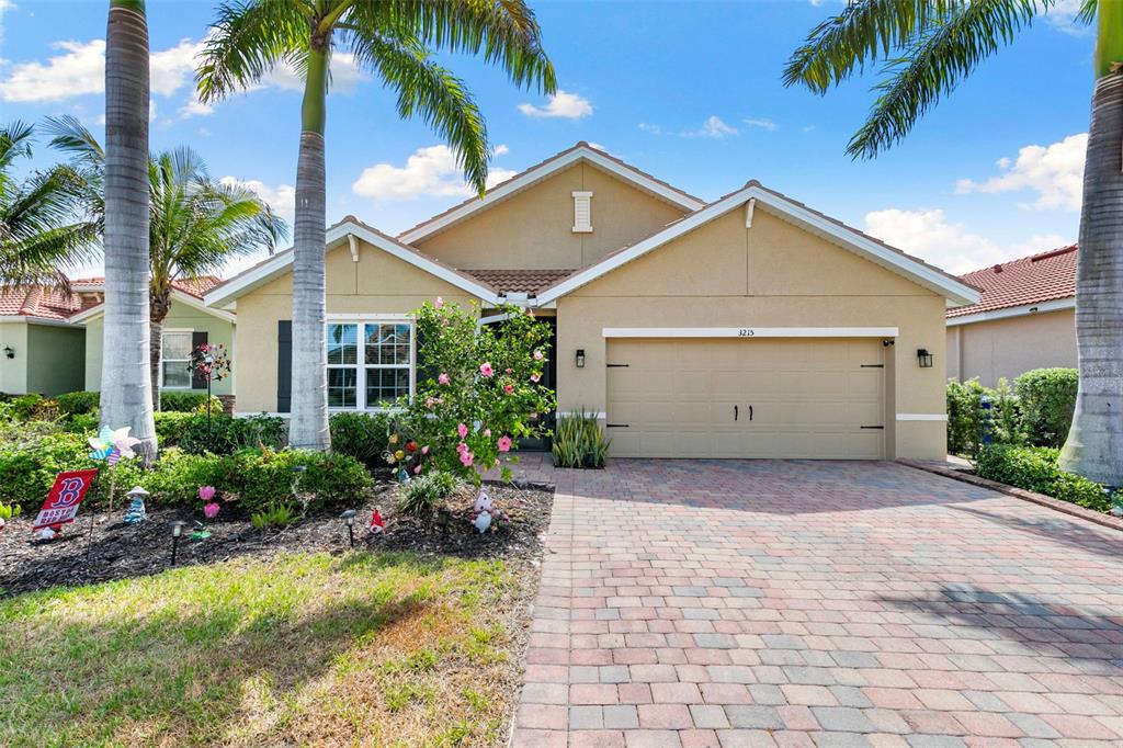 A single-story tan stucco house with a two-car garage and a brick paver driveway — 3215 BIRCHIN LANE, FORT MYERS, FL