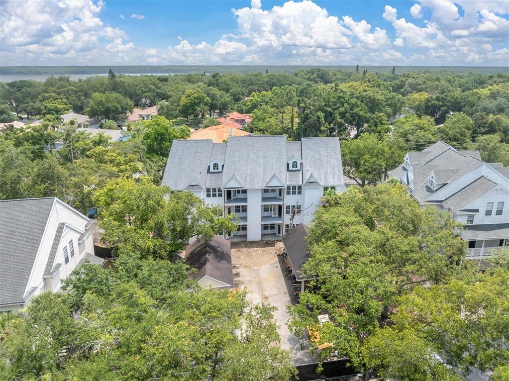 An aerial view shows a multi-story white building surrounded by trees and neighboring houses — 3313 HAVILAND COURT UNIT 203, PALM HARBOR, FL