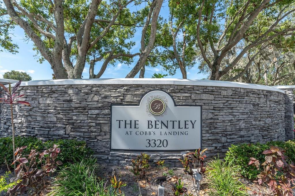 A stone monument sign for The Bentley at Cobb's Landing stands before large trees — 3313 HAVILAND COURT UNIT 203, PALM HARBOR, FL