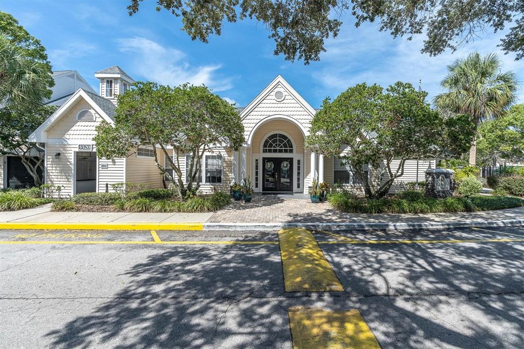 The exterior of a light-colored building features a central arched entrance and a speed bump — 3313 HAVILAND COURT UNIT 203, PALM HARBOR, FL