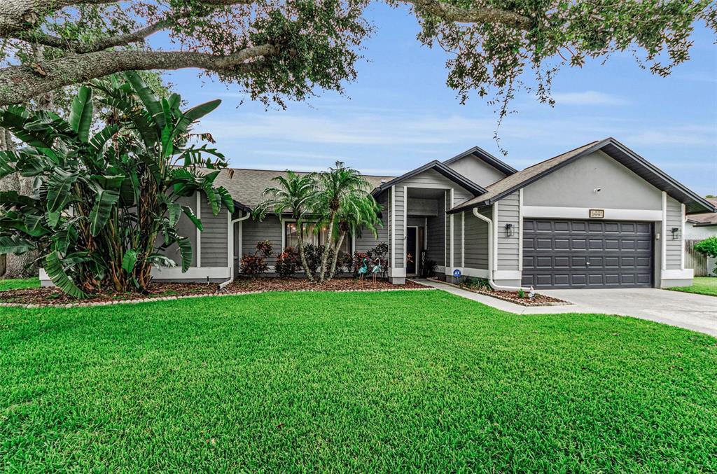 A single-story house with gray siding, a two-car garage, and a large front lawn — 5441 WORTHINGTON LOOP, PALM HARBOR, FL