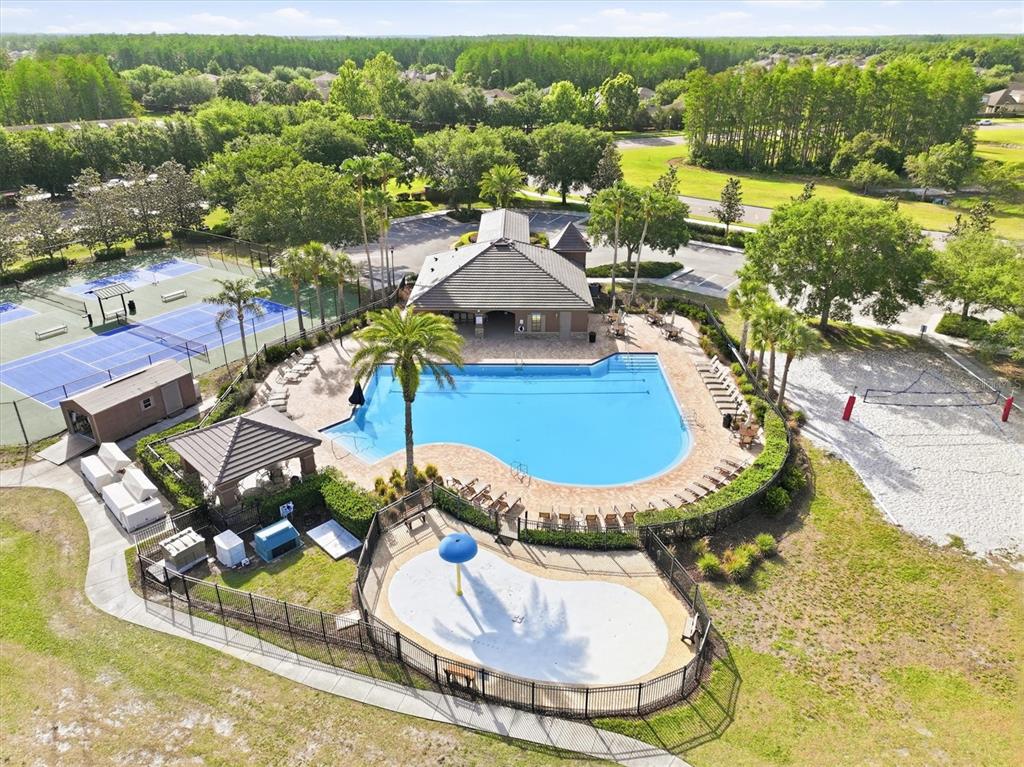 An aerial view shows a community swimming pool, splash pad, tennis courts, and a clubhouse — 3036 GIANNA WAY, LAND O LAKES, FL