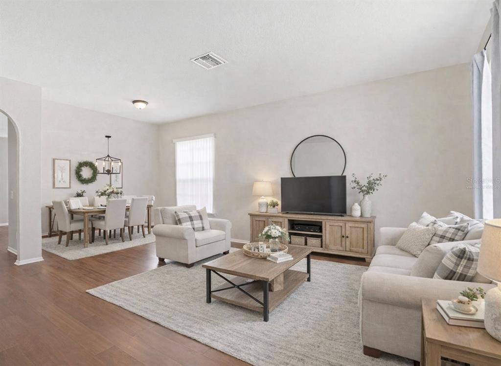 This living room features wood-look flooring, a neutral color palette, and an open dining area — 3036 GIANNA WAY, LAND O LAKES, FL
