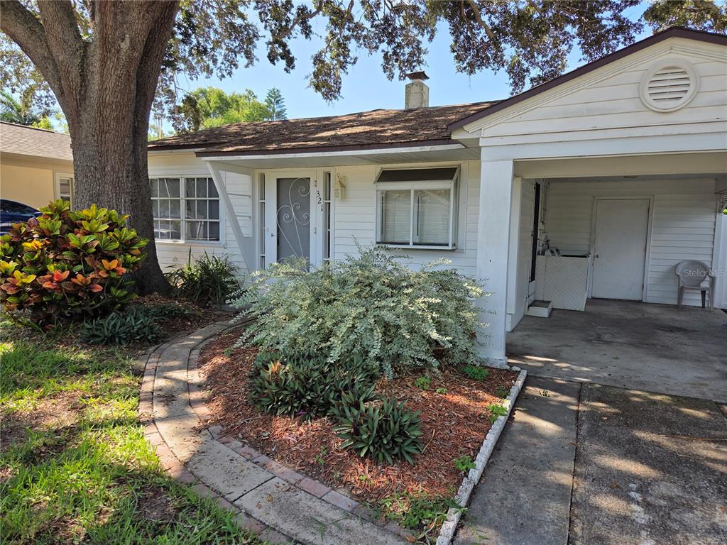 A white single-story house features a front porch, a carport, and a landscaped front yard — 321 WILDWOOD WAY, BELLEAIR, FL