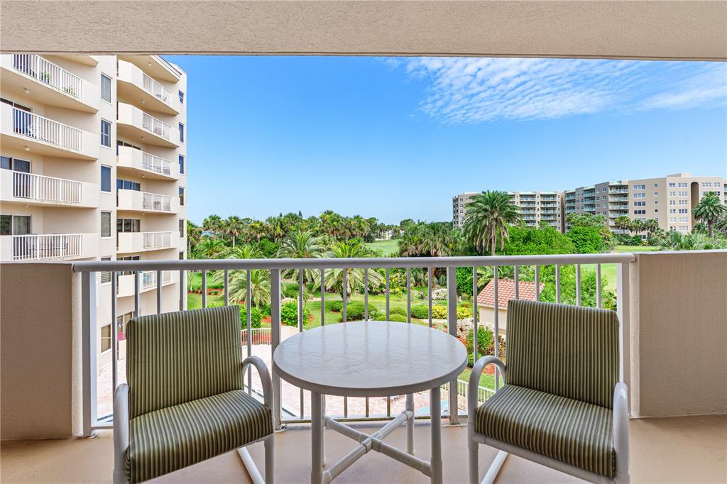 A high-angle view of a swimming pool, landscaped grounds, and apartment buildings under a blue sky — 3 OCEANS WEST BOULEVARD UNIT 3A7, DAYTONA BEACH SHORES, FL
