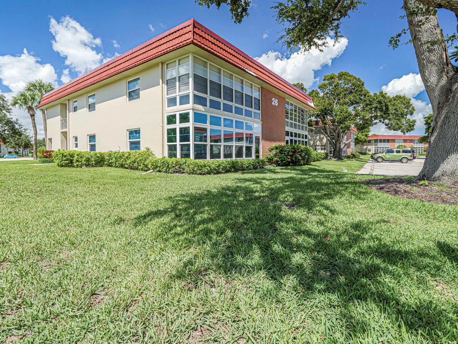 A two-story apartment building with a red roof, large windows, and a brick accent wall — 26 Pine Arbor Lane # 201, Vero Beach FL 32962, VERO BEACH, FL