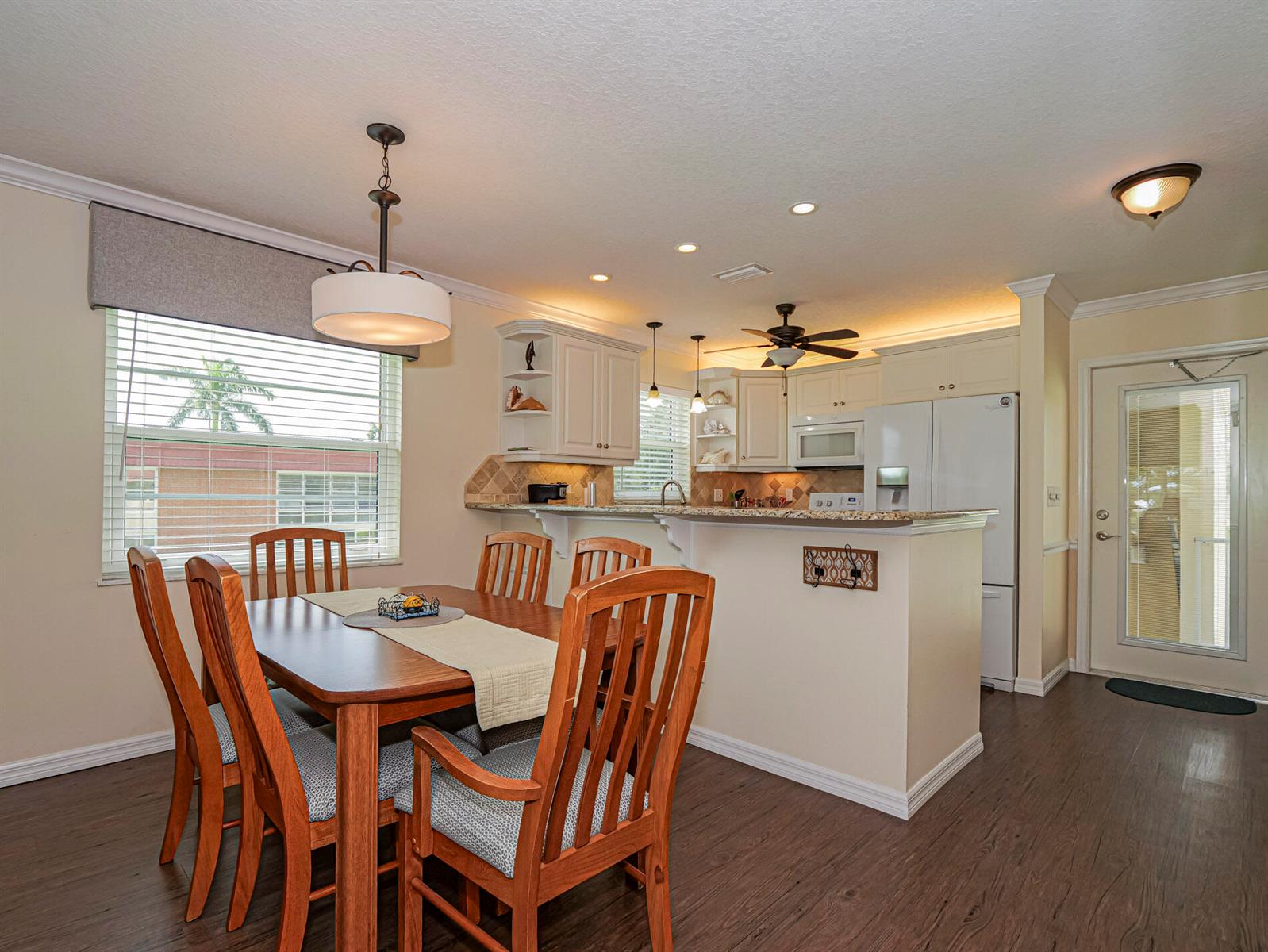 A dining area with a wooden table and chairs sits adjacent to a kitchen with cabinets — 26 Pine Arbor Lane # 201, Vero Beach FL 32962, VERO BEACH, FL