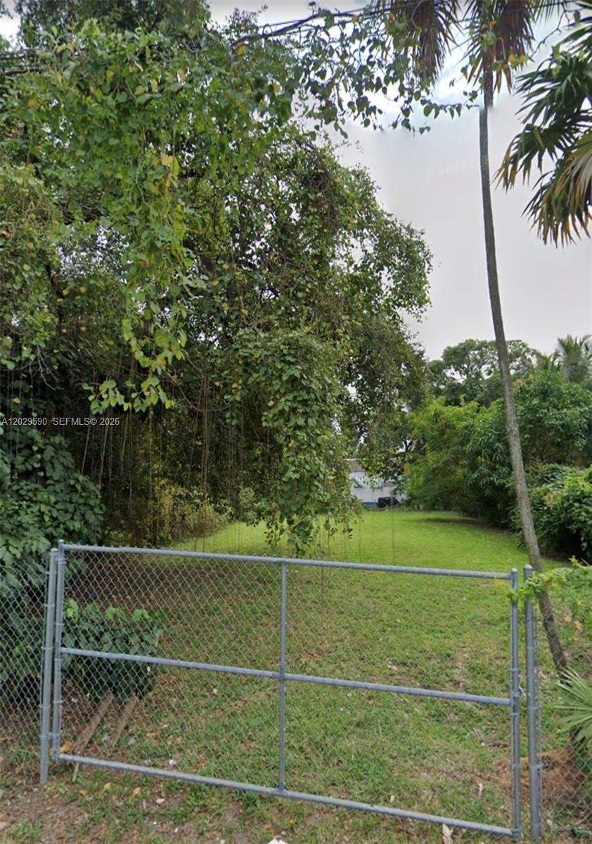 A chain-link gate opens to a grassy, tree-lined vacant lot — 276 NE 58th St, Miami FL 33137, MIAMI, FL