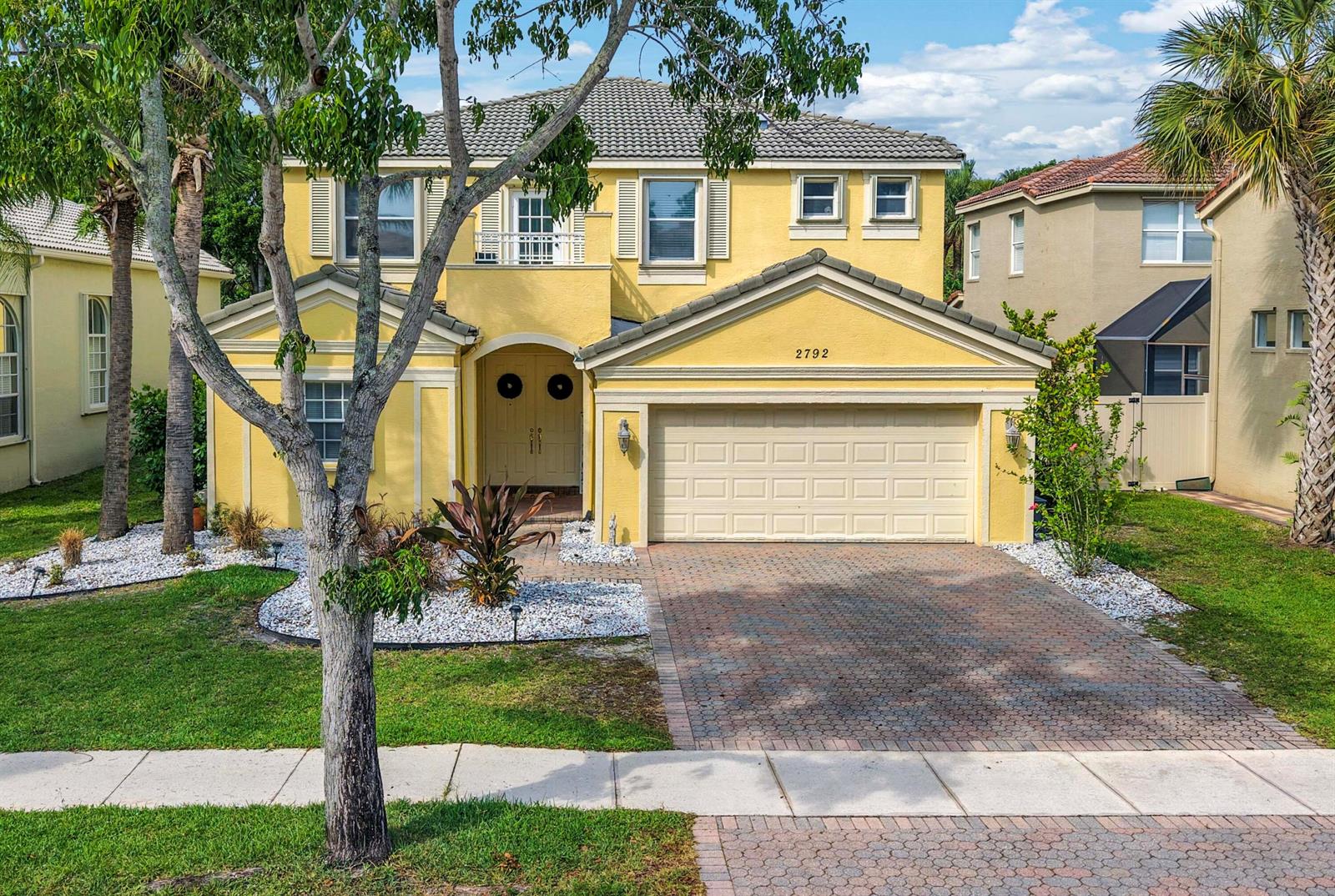 A two-story yellow house with a tiled roof, a two-car garage, and a paved driveway — 2792 Shaughnessy Drive, Wellington FL 33414, WELLINGTON, FL