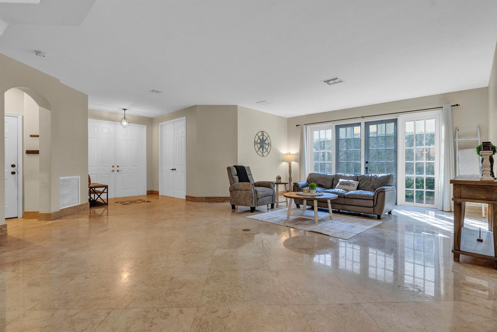 A spacious living room features light-colored tile flooring, a gray sofa, and double glass doors — 2792 Shaughnessy Drive, Wellington FL 33414, WELLINGTON, FL