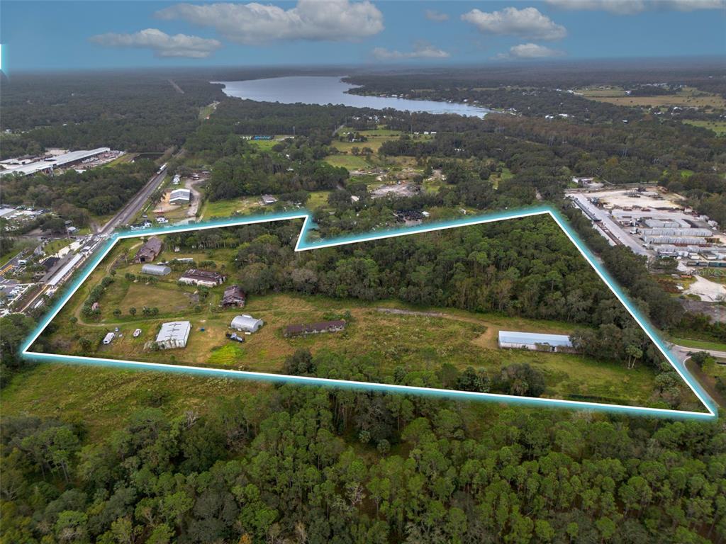 An aerial view shows a large, partially wooded plot of land with several buildings outlined — 2505 OLD NEW YORK AVENUE, DELAND, FL