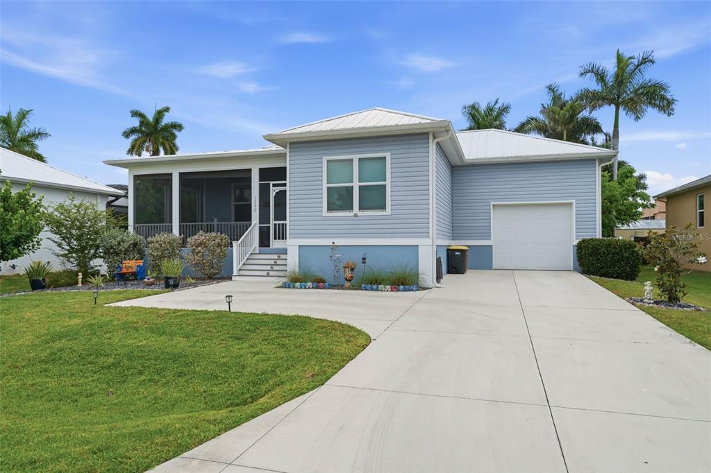 A light blue, single-story house with a white metal roof, screened porch, and concrete driveway — 1202 MCGREGOR STREET, PUNTA GORDA, FL