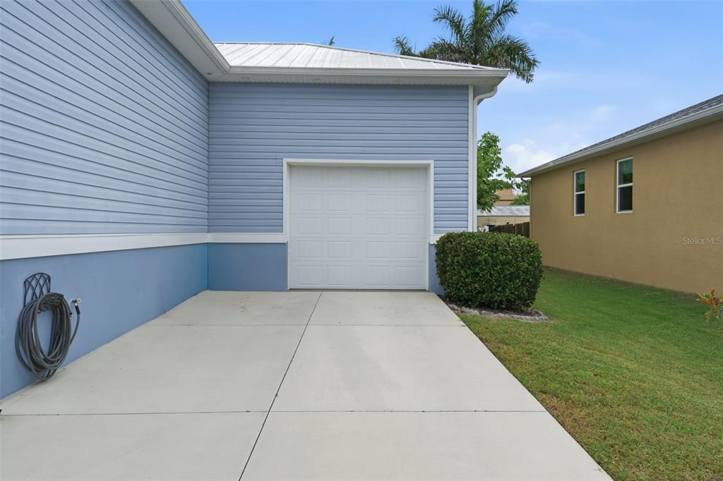 A light blue house features a white garage door, a concrete driveway, and a hose — 1202 MCGREGOR STREET, PUNTA GORDA, FL