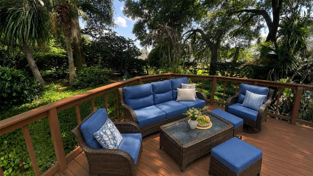 A wooden deck features wicker patio furniture with blue cushions and a glass-topped coffee table — 1320 SASSAFRAS AVENUE, ALTAMONTE SPRINGS, FL