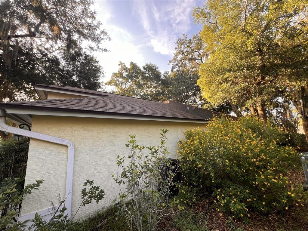 A yellow stucco house exterior features a dark shingled roof and a white downspout — 1320 SASSAFRAS AVENUE, ALTAMONTE SPRINGS, FL