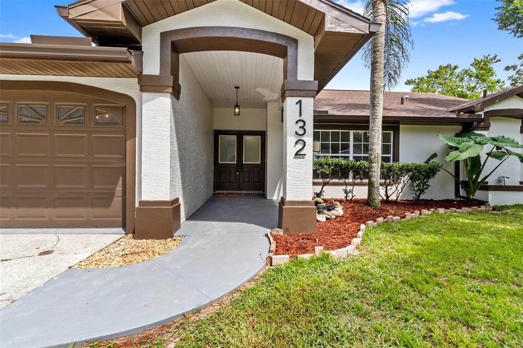 The exterior of a house features a covered entryway, a garage, and a front lawn — 132 GILLIAN DRIVE, SPRING HILL, FL