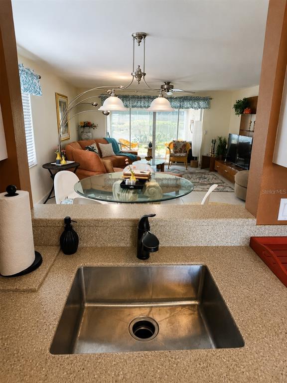 A kitchen sink overlooks a living and dining area with a glass table and sofa — 3720 EL POINIER COURT UNIT 515, SARASOTA, FL