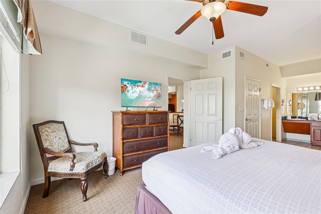 A bedroom features a bed with towel animals, a wooden dresser with a television, and chair — 8101 RESORT VILLAGE DRIVE UNIT 31210, ORLANDO, FL