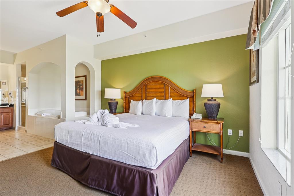 A bedroom features a king bed with a wooden headboard against a green accent wall — 8101 RESORT VILLAGE DRIVE UNIT 31210, ORLANDO, FL