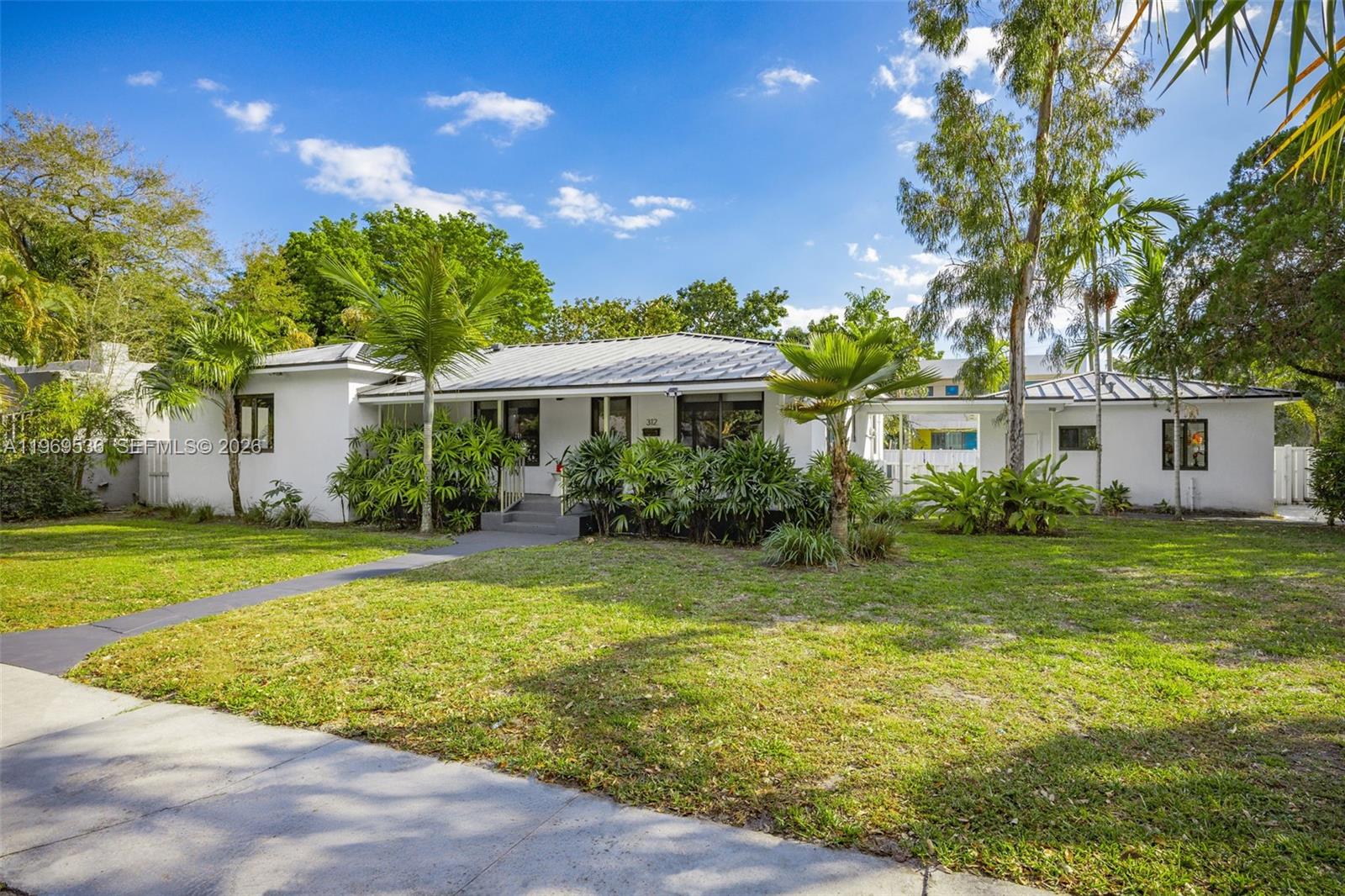 A white single-story house with a metal roof sits behind a grassy front yard — 312 NE 90th St, El Portal FL 33138, EL PORTAL, FL
