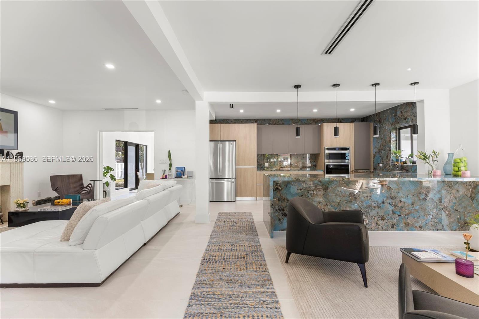 An open-concept living area features a white sofa, a kitchen with blue stone counters, and modern lighting — 312 NE 90th St, El Portal FL 33138, EL PORTAL, FL