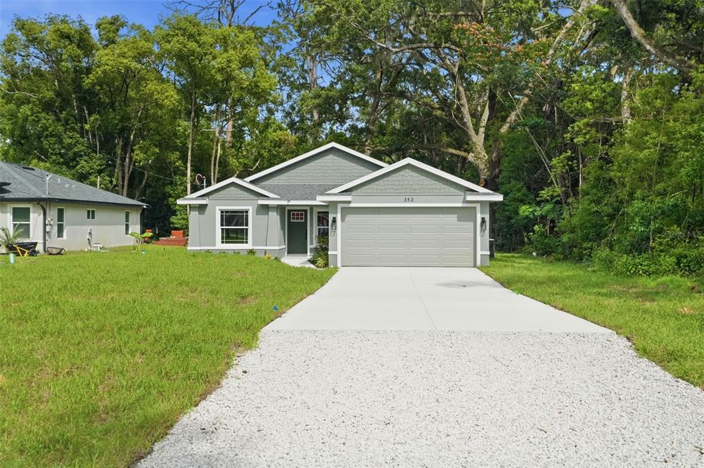 A single-story house with a gray exterior, a two-car garage, and a gravel driveway — 352 GARFIELD AVENUE, MASARYKTOWN, FL