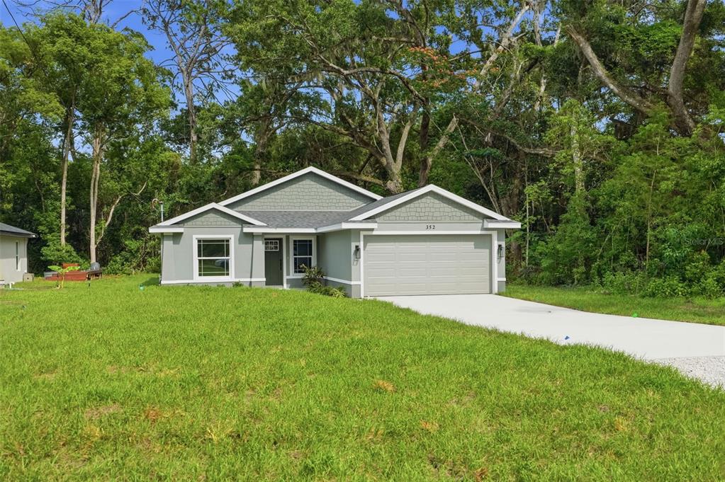 A single-story house with a gray exterior, a two-car garage, and a large front lawn — 352 GARFIELD AVENUE, MASARYKTOWN, FL
