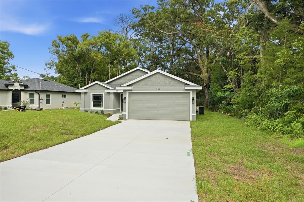 A single-story house with a gray exterior, a two-car garage, and a concrete driveway — 352 GARFIELD AVENUE, MASARYKTOWN, FL