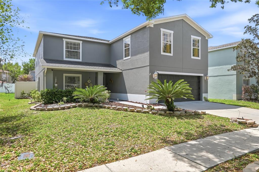 A two-story gray house features a front lawn, a driveway, and a two-car garage — 30902 TEMPLE STAND AVENUE, WESLEY CHAPEL, FL