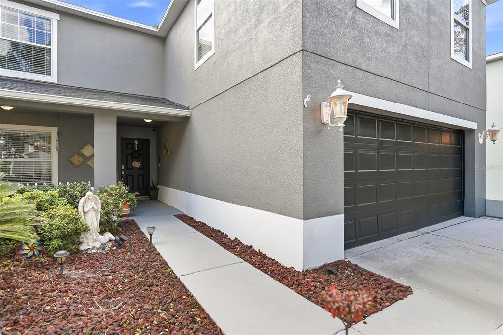 A gray two-story house features a dark garage door, a front walkway, and landscaping — 30902 TEMPLE STAND AVENUE, WESLEY CHAPEL, FL