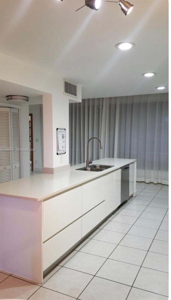A modern kitchen features a long white island with a sink and stainless steel dishwasher — 3301 Raleigh St # 4A, Hollywood FL 33021, HOLLYWOOD, FL