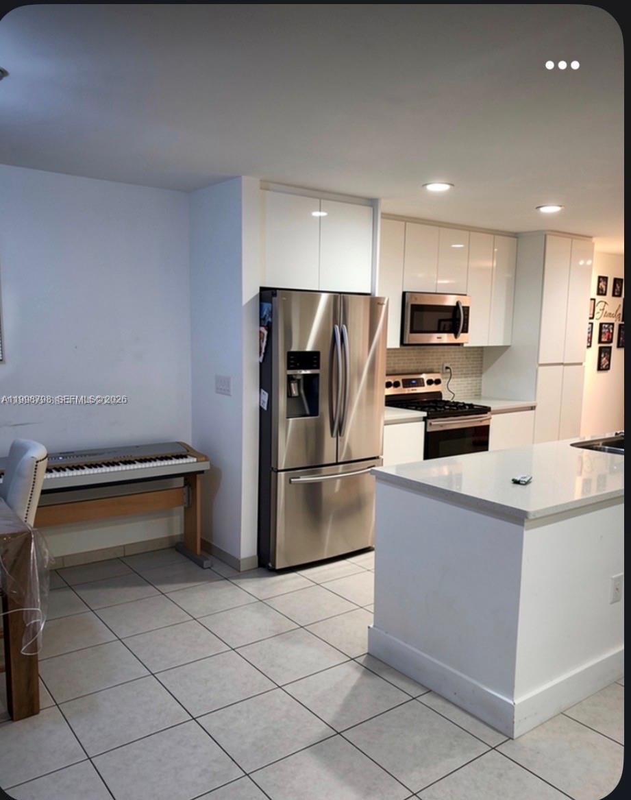 A modern kitchen features white cabinets, stainless steel appliances, and a central island — 3301 Raleigh St # 4A, Hollywood FL 33021, HOLLYWOOD, FL