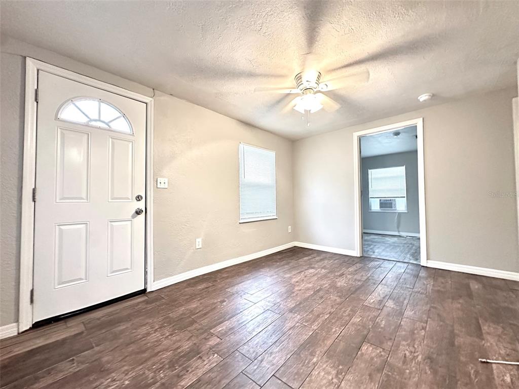 A living room features wood-look tile flooring, a ceiling fan, and a white entry door — 4111 28TH STREET N, ST PETERSBURG, FL