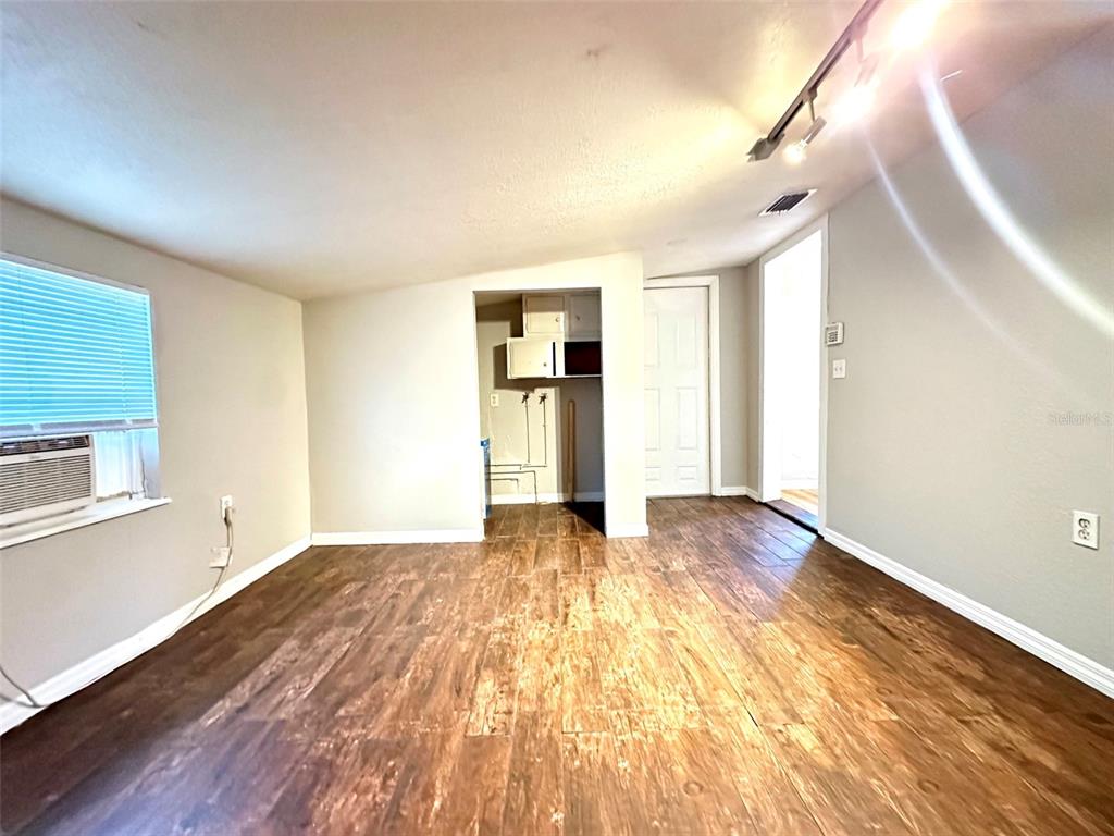 An interior room features wood-look flooring, a window air conditioning unit, and a doorway opening — 4111 28TH STREET N, ST PETERSBURG, FL