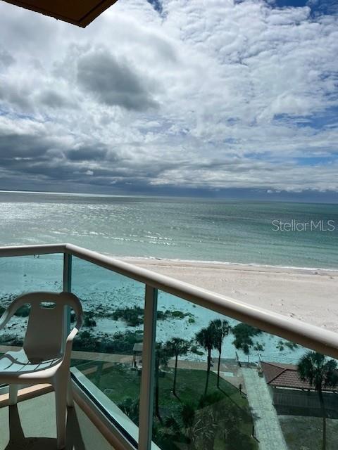 A balcony with a white plastic chair overlooks a sandy beach and the ocean — 880 MANDALAY AVENUE UNIT S713, CLEARWATER BEACH, FL