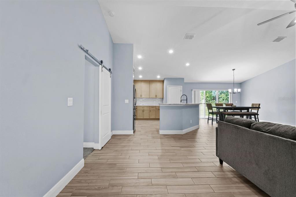 A light blue open-concept living area features wood-look tile flooring and a kitchen with cabinets — 13218 BARNEVELDE RD, WEEKI WACHEE, FL