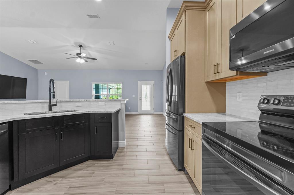 A kitchen with dark lower cabinets, light upper cabinets, and a view into the living area — 13218 BARNEVELDE RD, WEEKI WACHEE, FL