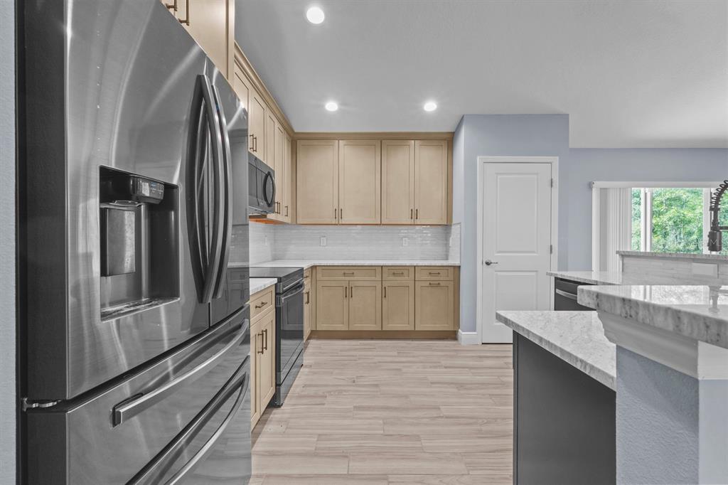 A kitchen features light wood cabinets, stainless steel appliances, and a white marble-patterned countertop — 13218 BARNEVELDE RD, WEEKI WACHEE, FL