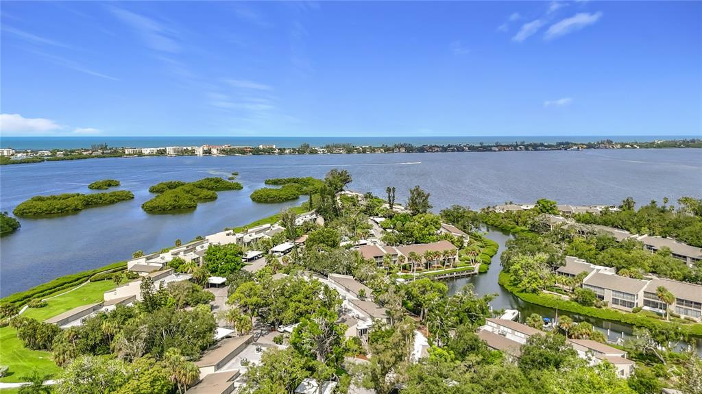 An aerial view of a waterfront residential complex surrounded by lush trees and mangroves — 1601 PELICAN POINT DRIVE UNIT 215, SARASOTA, FL