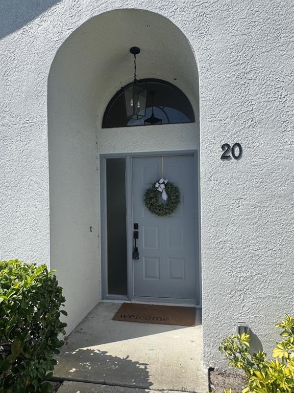 A gray front door with a wreath and a sidelight sits under a recessed archway — 2749 COUNTRYSIDE BOULEVARD UNIT 20, CLEARWATER, FL