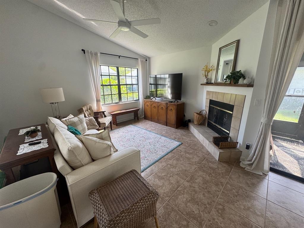 A living room features a fireplace, a television on a wooden console, and tile flooring — 2749 COUNTRYSIDE BOULEVARD UNIT 20, CLEARWATER, FL