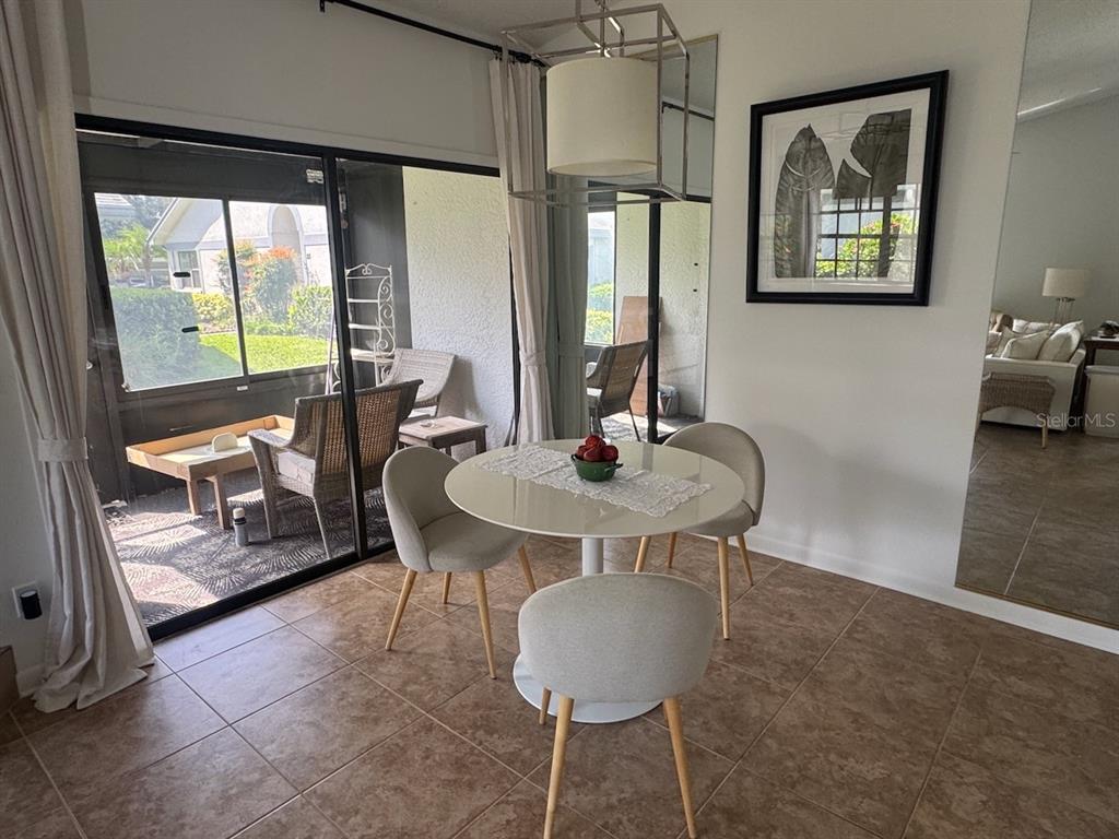 A dining area features a round table, three chairs, and a sliding door to a patio — 2749 COUNTRYSIDE BOULEVARD UNIT 20, CLEARWATER, FL