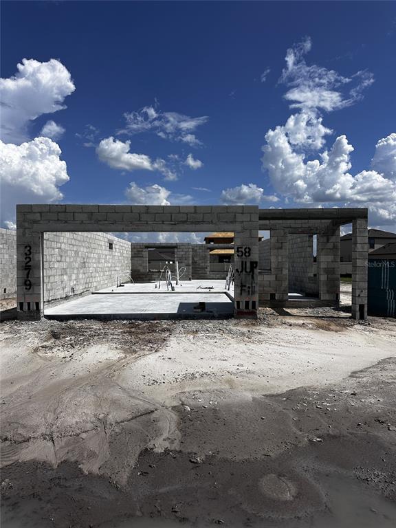 A residential construction site shows concrete block walls and a slab foundation under a blue sky — 3279 CUP DRIVE, LAKELAND, FL